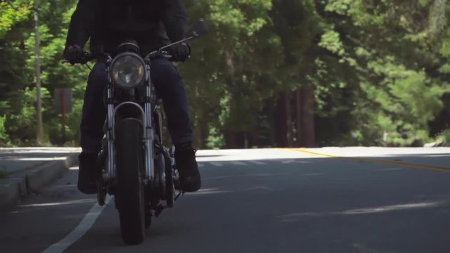 Slow Motion of Motorcyclist With Leather Jacket Coming to a Stop on a Wooded Road