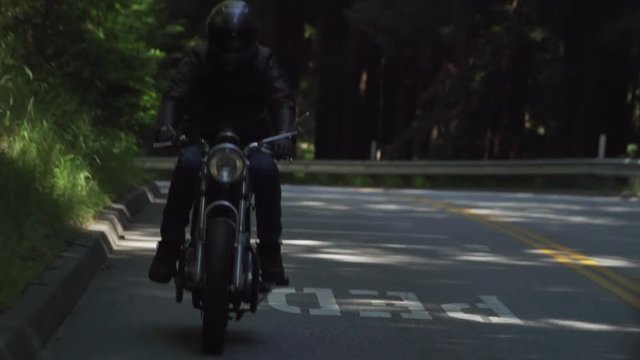 Motorcyclist With Leather Jacket Riding on a Wooded Road