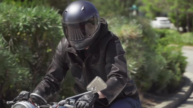 Slow Motion of Motorcyclist With Leather Jacket Starting on a Turn From a Stop
