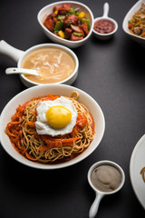 Assorted Indo chinese food in group includes non vegetarian or chicken Schezwan/Szechuan hakka noodles, fried rice, manchurian, egg american chop suey, soup with spoon and chop sticks, selective focus
