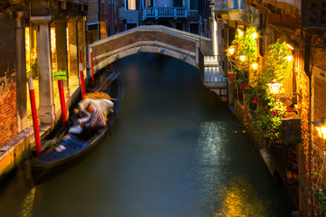 Gondolier is resting waiting for tourists, Venetian canals at night.