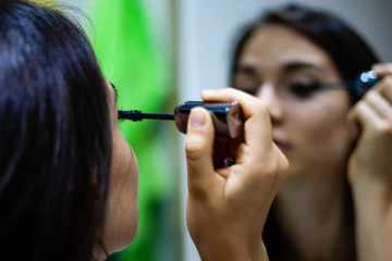 Girl applying mascara in the mirror