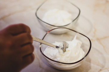 Hand putting cream on transparent bowl