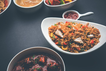 Assorted Indo chinese food in group includes non vegetarian or chicken Schezwan/Szechuan hakka noodles, fried rice, manchurian, egg american chop suey, soup with spoon and chop sticks, selective focus