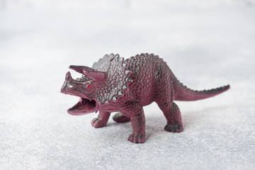 Dinosaur on a gray background. Plastic rubber toy. Selective focus.