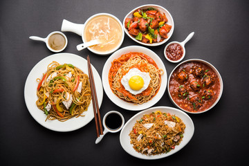 Assorted Indo chinese food in group includes non vegetarian or chicken Schezwan/Szechuan hakka noodles, fried rice, manchurian, egg american chop suey, soup with spoon and chop sticks, selective focus