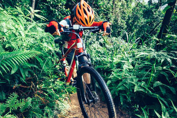 Tired woman cyclist have a rest while cross country biking in tropical forest