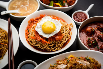 Assorted Indo chinese food in group includes non vegetarian or chicken Schezwan/Szechuan hakka noodles, fried rice, manchurian, egg american chop suey, soup with spoon and chop sticks, selective focus