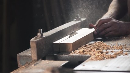 Hands of a carpenter sawing a piece of wood with cabinet table saw - front view.