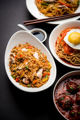 Assorted Indo chinese food in group includes non vegetarian or chicken Schezwan/Szechuan hakka noodles, fried rice, manchurian, egg american chop suey, soup with spoon and chop sticks, selective focus