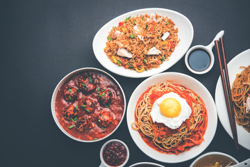 Assorted Indo chinese food in group includes non vegetarian or chicken Schezwan/Szechuan hakka noodles, fried rice, manchurian, egg american chop suey, soup with spoon and chop sticks, selective focus