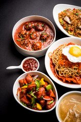 Assorted Indo chinese food in group includes non vegetarian or chicken Schezwan/Szechuan hakka noodles, fried rice, manchurian, egg american chop suey, soup with spoon and chop sticks, selective focus