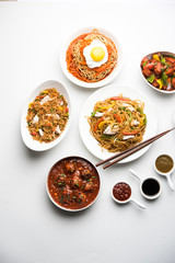 Assorted Indo chinese food in group includes non vegetarian or chicken Schezwan/Szechuan hakka noodles, fried rice, manchurian, egg american chop suey, soup with spoon and chop sticks, selective focus
