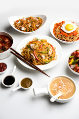 Assorted Indo chinese food in group includes non vegetarian or chicken Schezwan/Szechuan hakka noodles, fried rice, manchurian, egg american chop suey, soup with spoon and chop sticks, selective focus