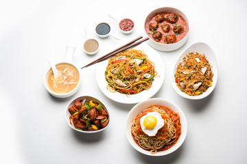 Assorted Indo chinese food in group includes non vegetarian or chicken Schezwan/Szechuan hakka noodles, fried rice, manchurian, egg american chop suey, soup with spoon and chop sticks, selective focus