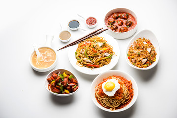 Assorted Indo chinese food in group includes non vegetarian or chicken Schezwan/Szechuan hakka noodles, fried rice, manchurian, egg american chop suey, soup with spoon and chop sticks, selective focus