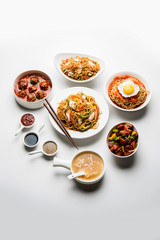 Assorted Indo chinese food in group includes non vegetarian or chicken Schezwan/Szechuan hakka noodles, fried rice, manchurian, egg american chop suey, soup with spoon and chop sticks, selective focus