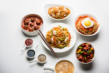 Assorted Indo chinese food in group includes non vegetarian or chicken Schezwan/Szechuan hakka noodles, fried rice, manchurian, egg american chop suey, soup with spoon and chop sticks, selective focus