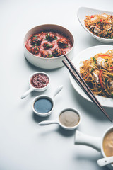 Assorted Indo chinese food in group includes non vegetarian or chicken Schezwan/Szechuan hakka noodles, fried rice, manchurian, egg american chop suey, soup with spoon and chop sticks, selective focus