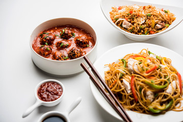 Assorted Indo chinese food in group includes non vegetarian or chicken Schezwan/Szechuan hakka noodles, fried rice, manchurian, egg american chop suey, soup with spoon and chop sticks, selective focus