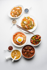 Assorted Indo chinese food in group includes non vegetarian or chicken Schezwan/Szechuan hakka noodles, fried rice, manchurian, egg american chop suey, soup with spoon and chop sticks, selective focus