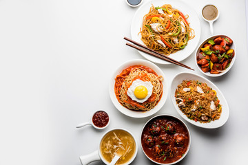 Assorted Indo chinese food in group includes non vegetarian or chicken Schezwan/Szechuan hakka noodles, fried rice, manchurian, egg american chop suey, soup with spoon and chop sticks, selective focus