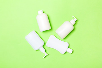 Naklejka premium Set of White Cosmetic containers isolated on green background, top view with copy space. Group of plastic bodycare bottle containers with empty space for you design