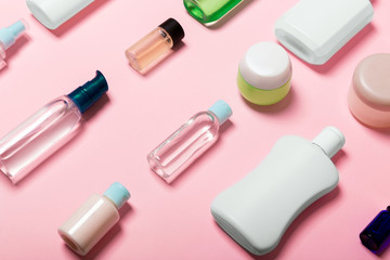 Top view of cosmetic containers, sprays, jars and bottles on pink background. Close-up view with empty space for your design