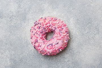 Pink doughnut on a grey background. Top view Flat lay.