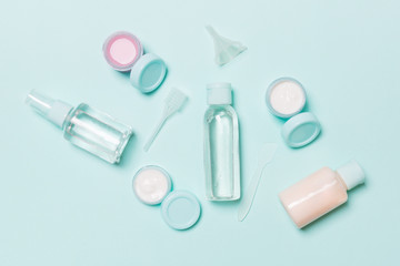 Set of travel size cosmetic bottles on blue background. Flat lay of cream jars. Top view of bodycare style concept