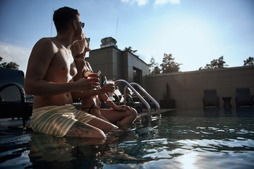 Young lovely couple spending time together in swimming pool