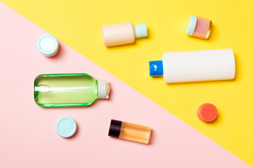 Top view of cosmetic containers, sprays, jars and bottles on pink background. Close-up view with empty space for your design