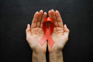 Symbol of human immunodeficiency virus disease. Red ribbon. A helping hand and support.