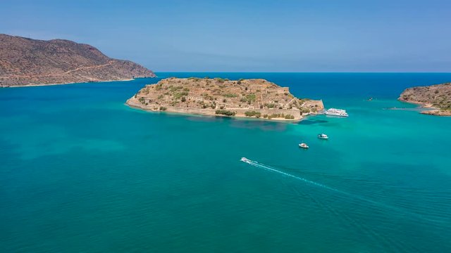Aerial hyperlapse of sightseeing boats around the ancient Venetian fortress island of Spinalonga in Crete, Greece