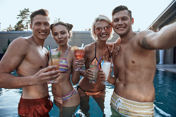 Young friends making selfie while situating in the pool