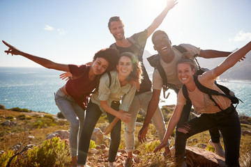 Millennial friends on a hiking trip reach the summit and have fun posing for photos