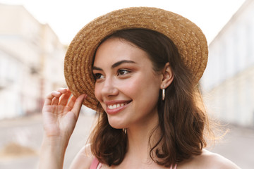 Photo closeup of glamorous young woman wearing summer straw hat walking on city street
