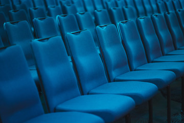 Blue empty seats in the audience prepared for the participants of the conference or presentation. 