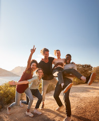 Five millennial friends on a road trip have fun posing for photos on a coastal path, full length - obrazy, fototapety, plakaty