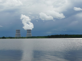 Cooling towers and steam. Lakeside. Overcast sky.