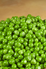 Green peas are piled on a light background. Vertical image.