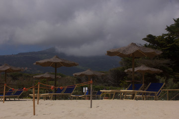 a nice day by the beach with beach lies and umbrellas turn in a few second to a day with a storm