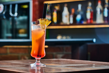 Drink cocktail with pinapple in a night bar. Blurry pub background. Copy space