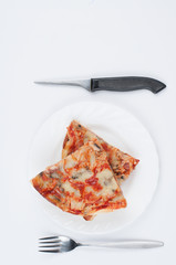 A delicious homemade pizza on a plate isolated on a white background. Pizza on a plate with a knife and a fork