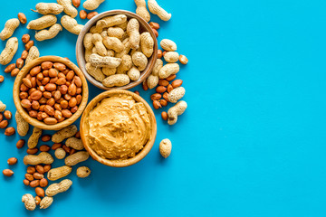 Make peanut butter with nuts and paste in bowl on blue background top view copyspace