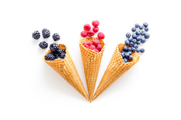 Summer breakfast with fresh berries in waffle cones on white background top view