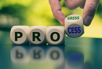 Hand turns a cube and changes the word "process" to "progress".