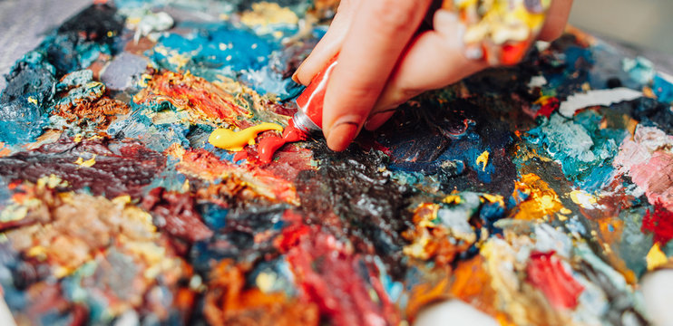 Closeup Of Colorful Palette. Cropped Shot Of Lefthanded Female Artist Mixing Acrylic Paint.