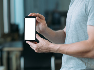 Electronics and gadgets. Closeup of white mockup smartphone screen in man hands. Copy space.