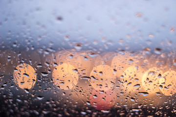 Ventana con gotas de agua de lluvia en cristal con luces desenfocadas de fondo